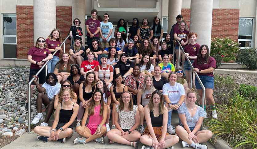 A large group of students from the Public Service Residential College sit and stand on the steps to Anspach Hall.